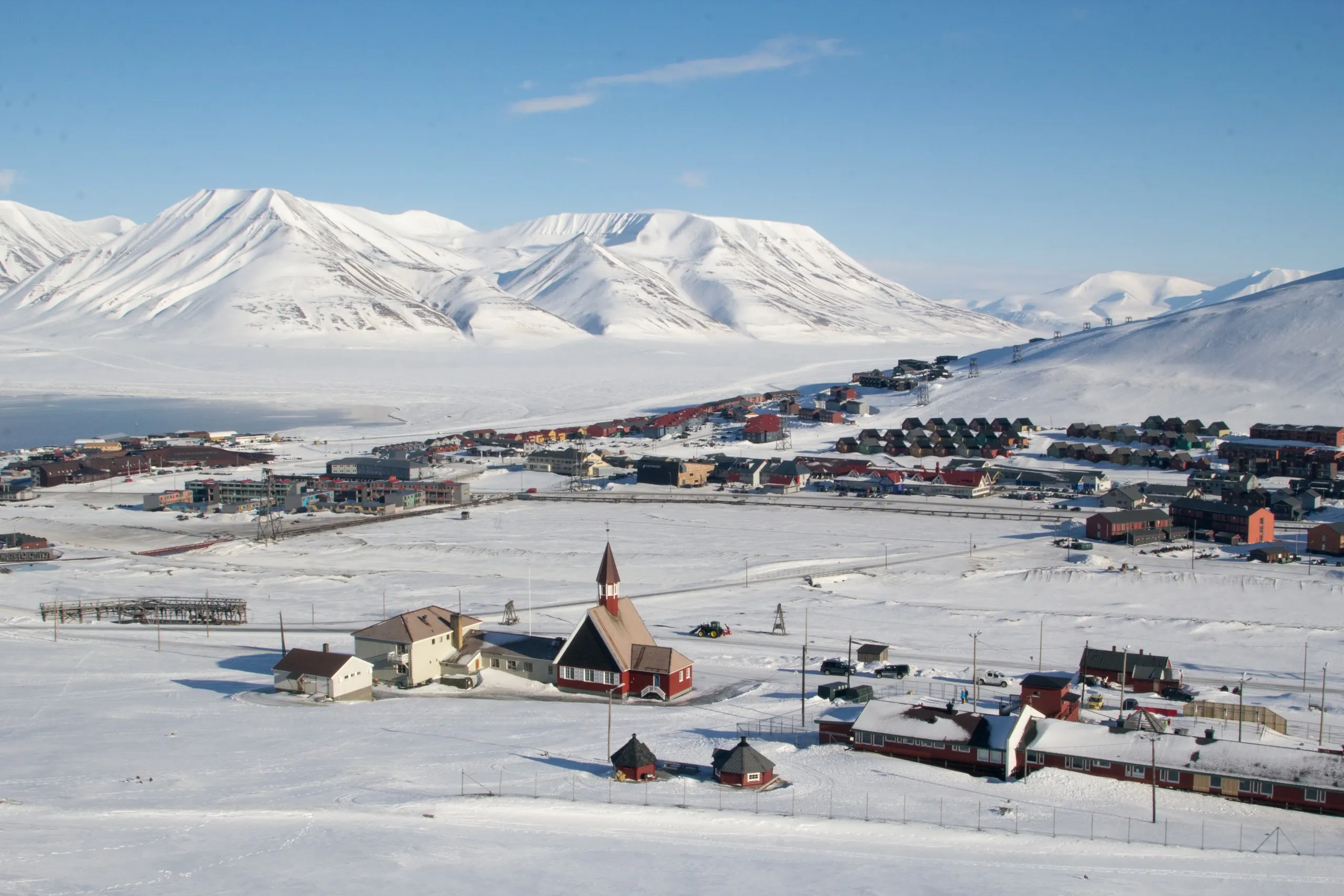 Longyearbyen church and town beneath snowy peaks in light winter