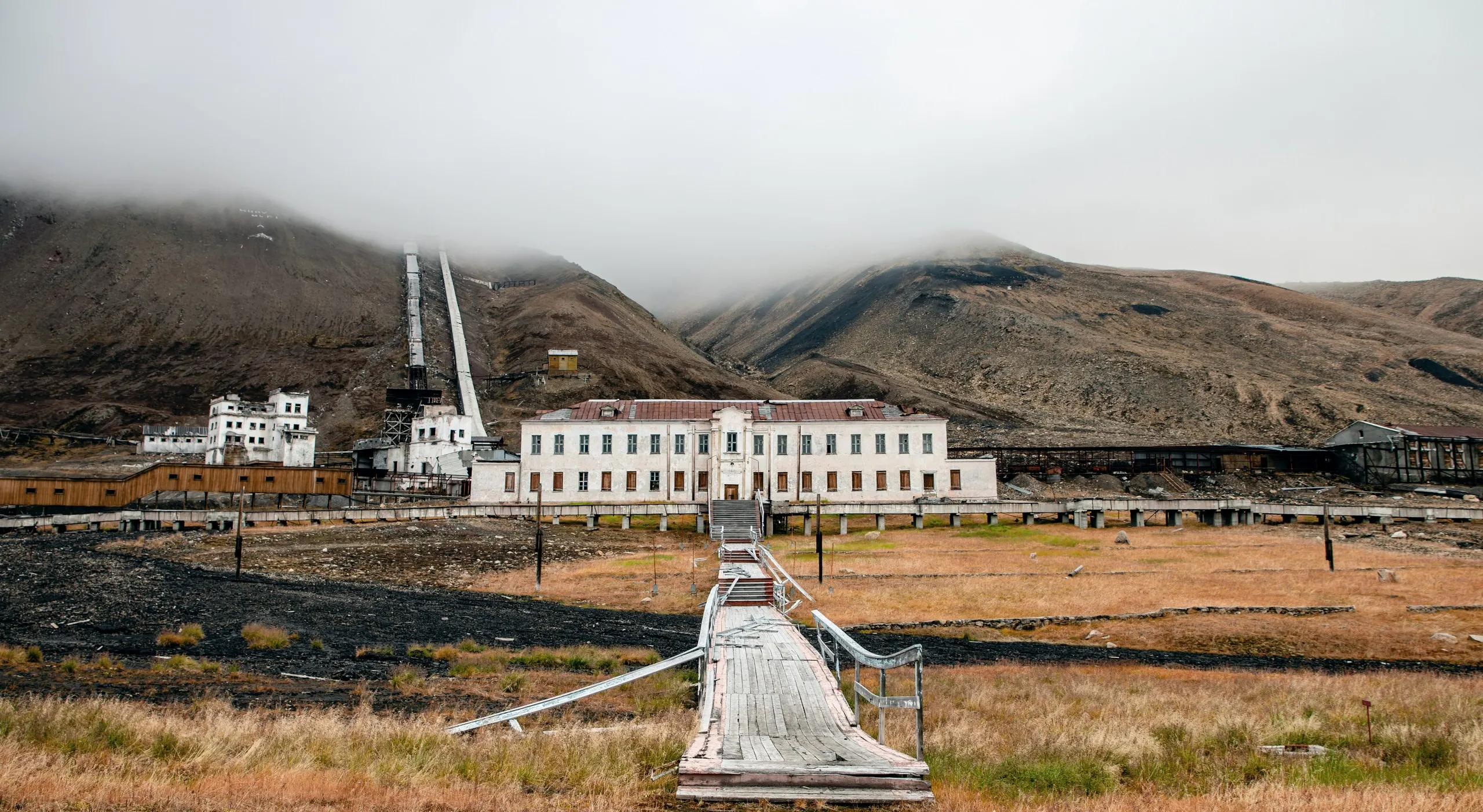 Abandoned buildings of Pyramiden standing under low fog