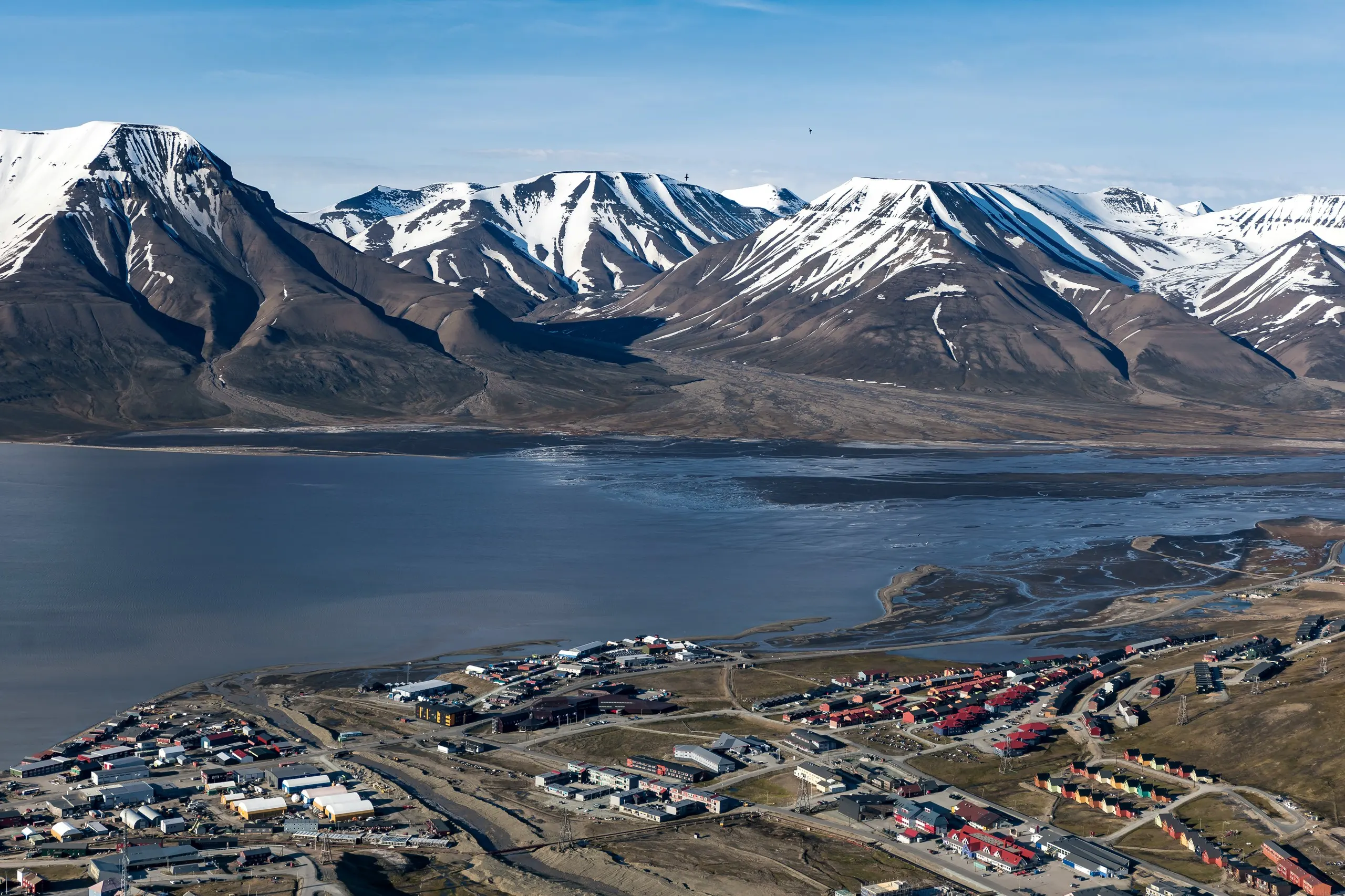 Aerial view of Longyearbyen between fjord and snowy peaks in summer