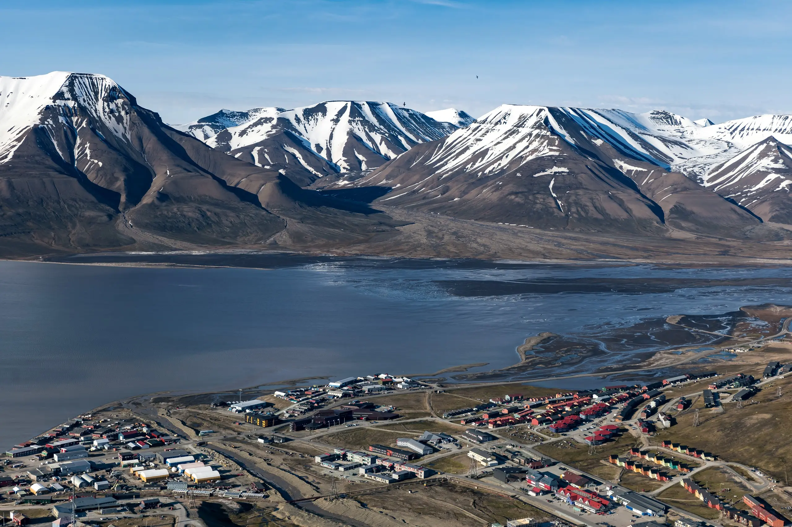 Aerial view of Longyearbyen between fjord and snowy peaks in summer