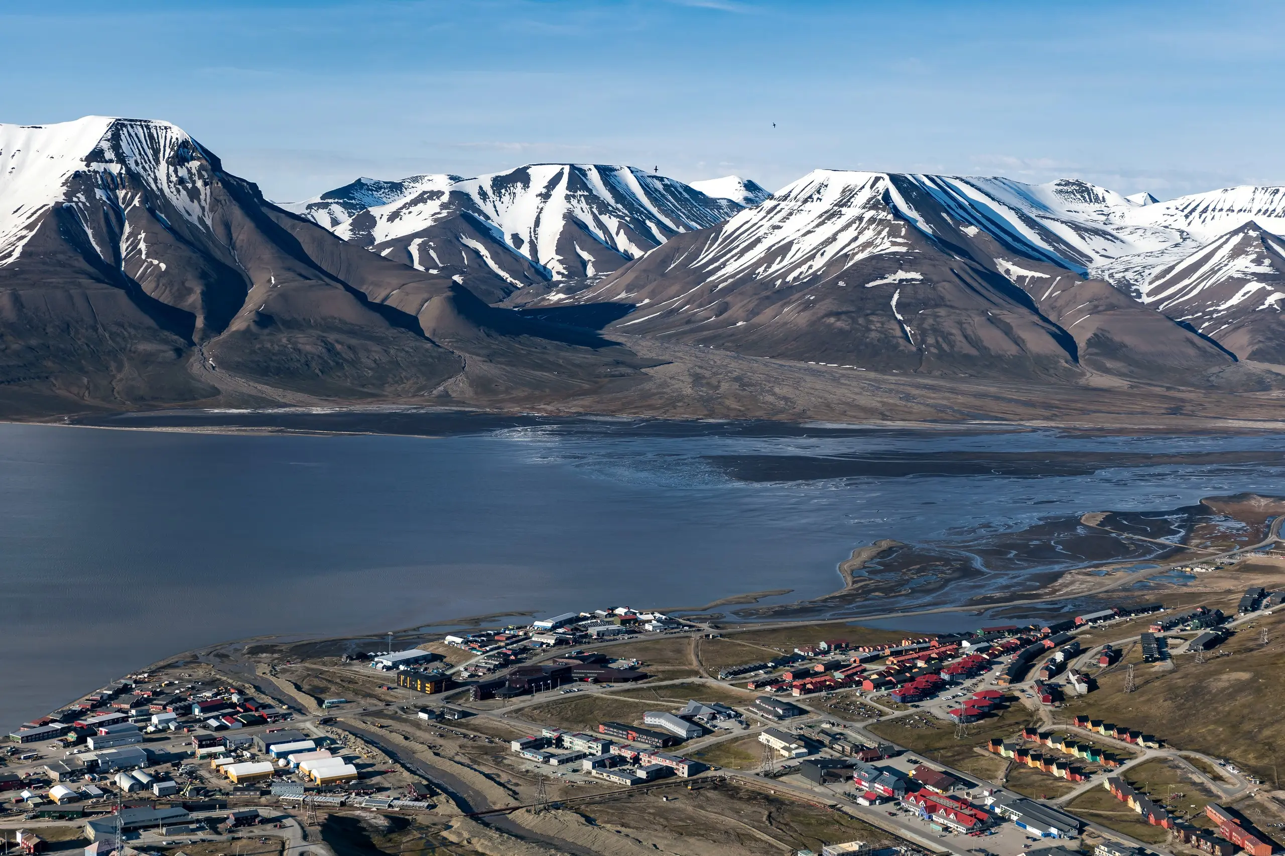 Aerial view of Longyearbyen town beside the fjord and snow-streaked peaks in summer