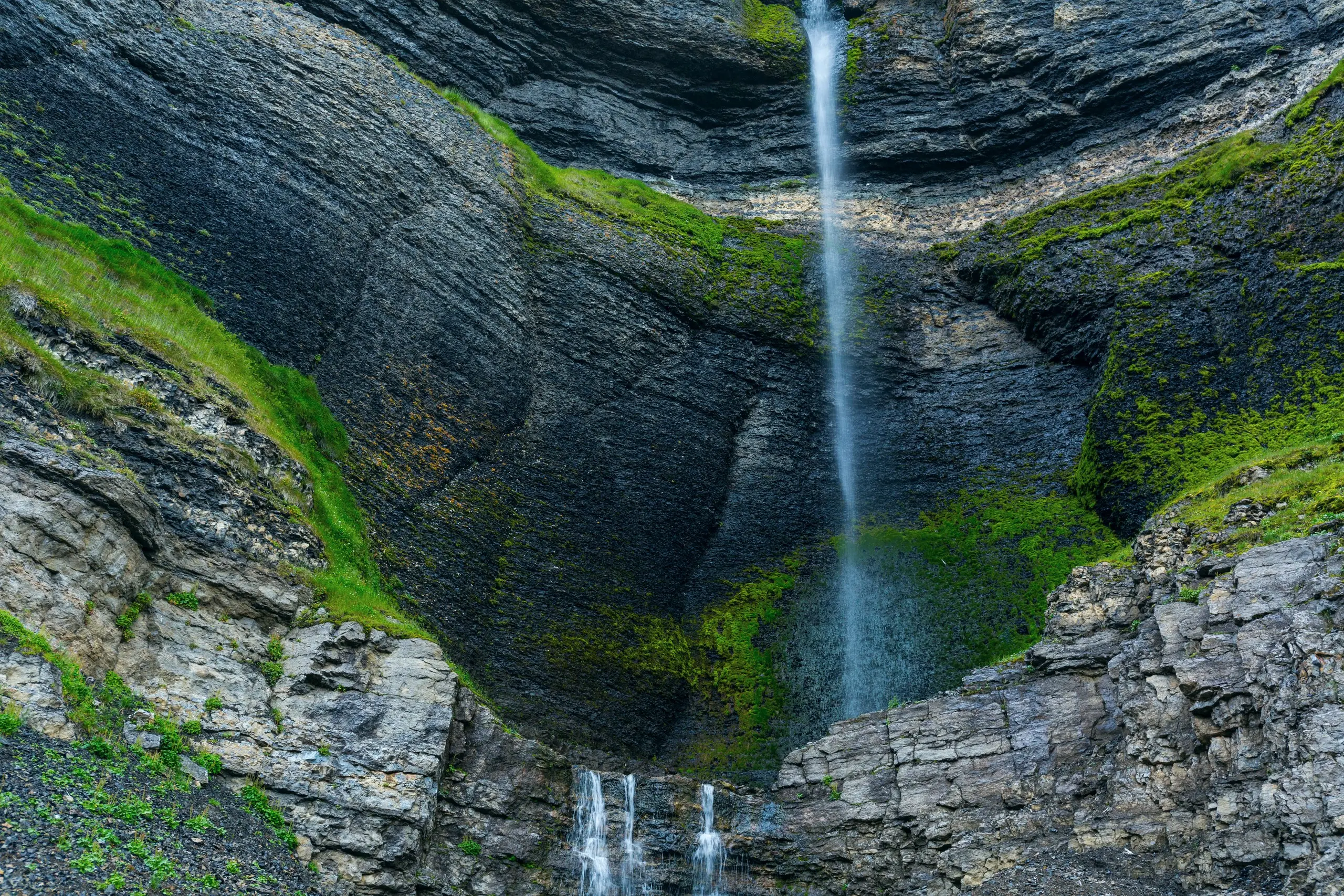 Waterfall streaking down a mossy cliff face on a summer hiking route
