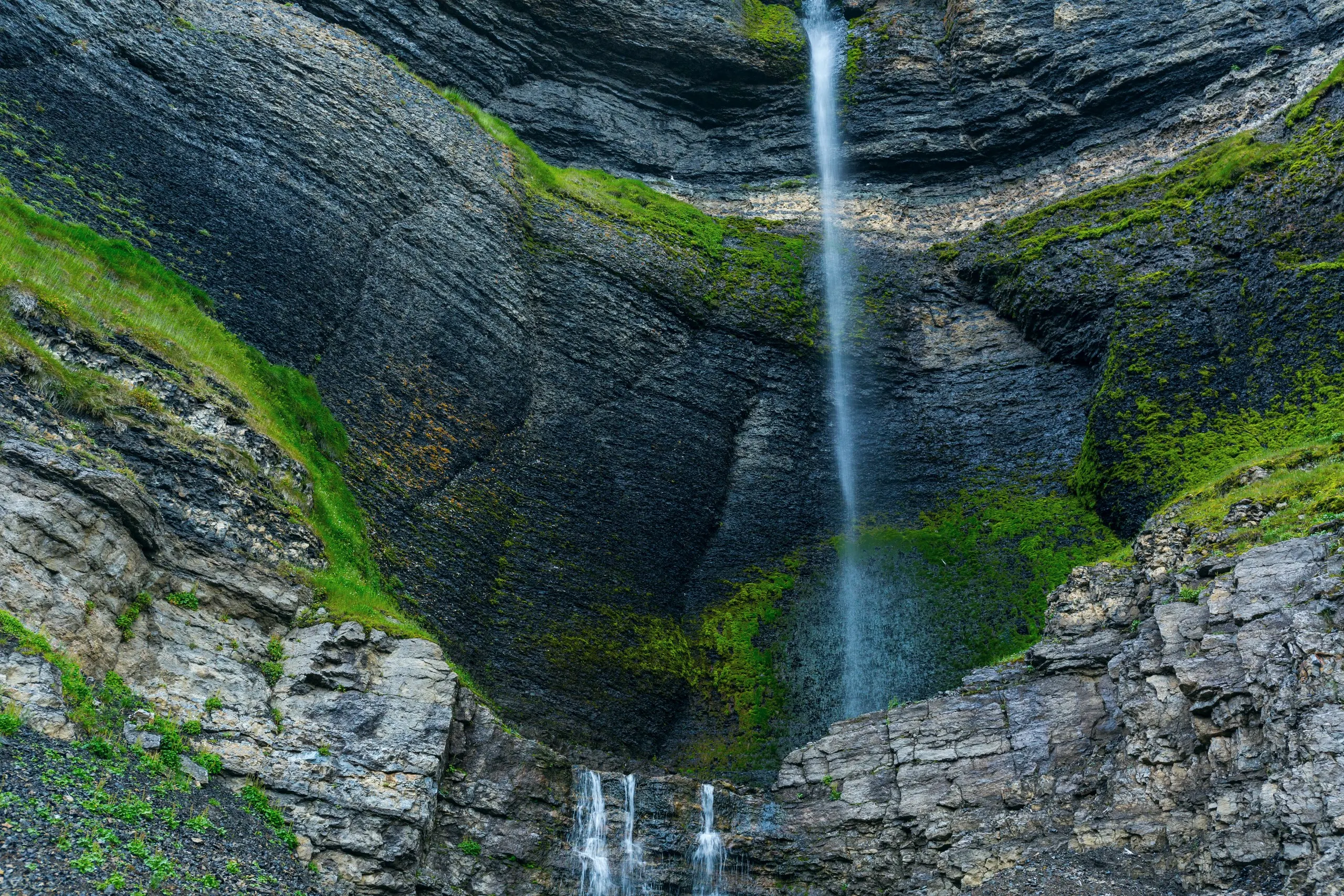 Waterfall streaking down a mossy cliff face on a summer hiking route