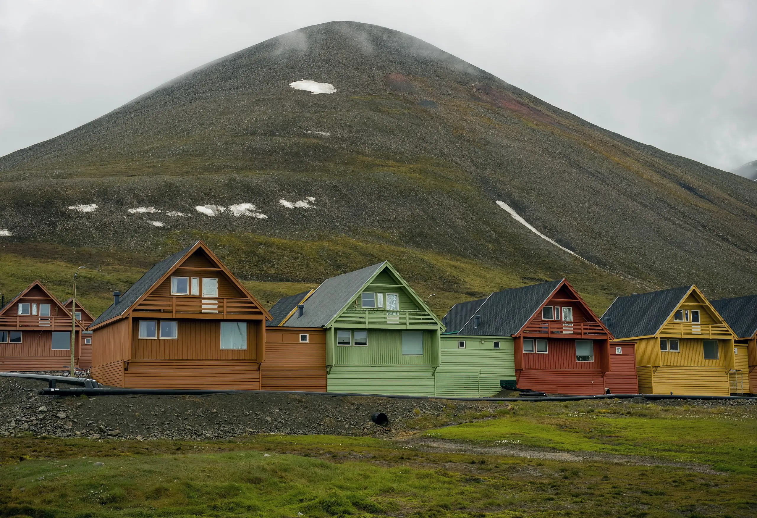 Colorful Longyearbyen houses below a mist-capped mountain in summer