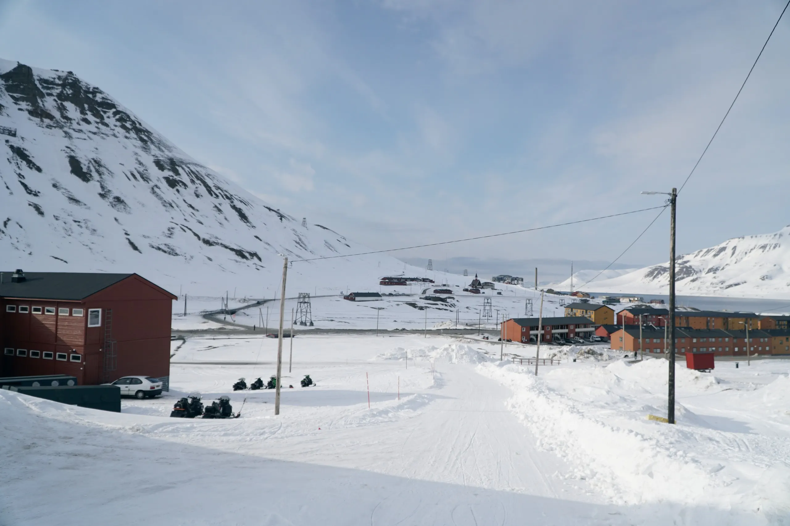 Snowmobiles parked across wintry Longyearbyen under low light