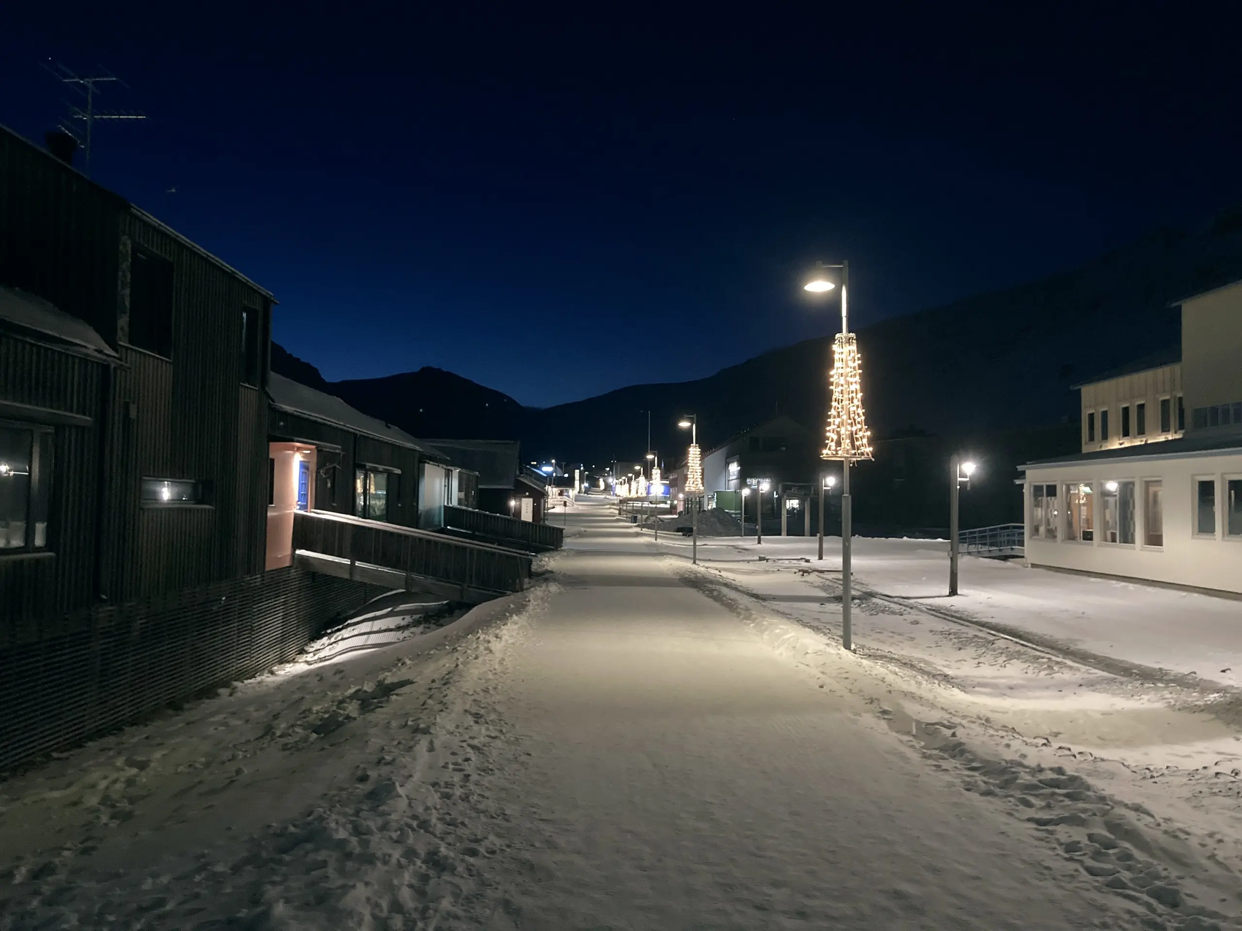 Snowy street with festive light cones in the polar night