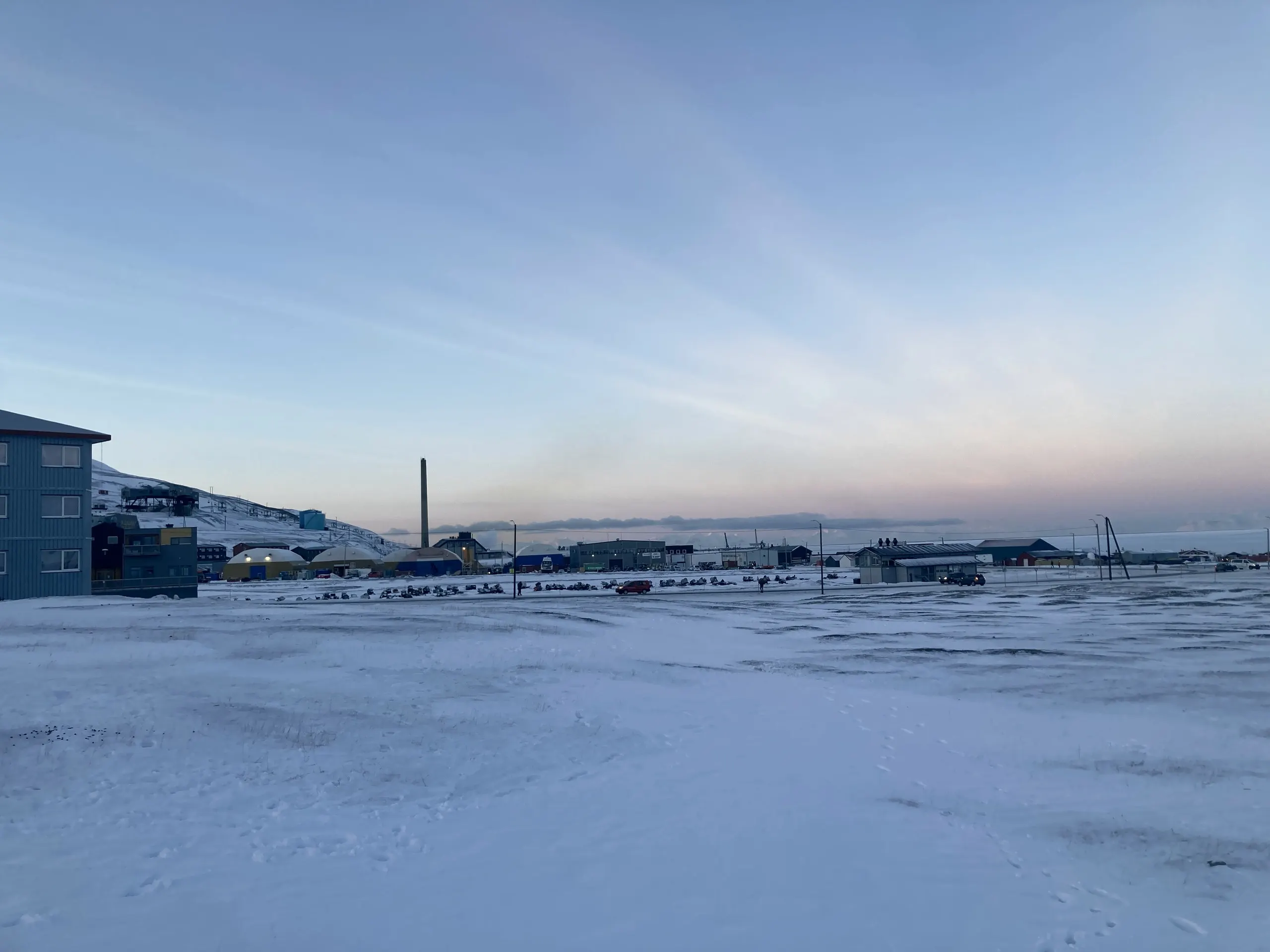 Industrial Arctic harbour under a pastel dawn sky at a remote settlement