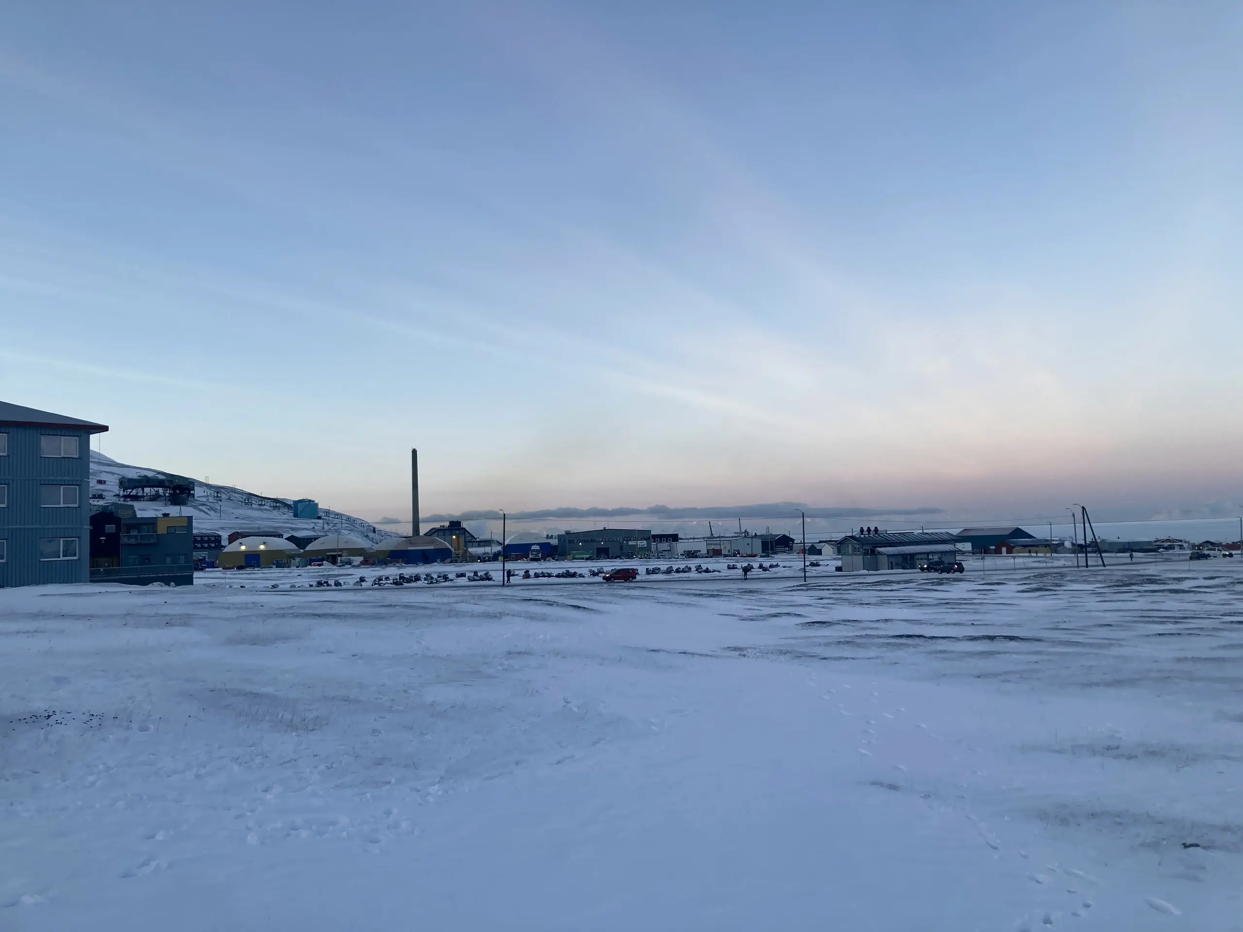 Industrial Arctic harbour under a pastel dawn sky at a remote settlement