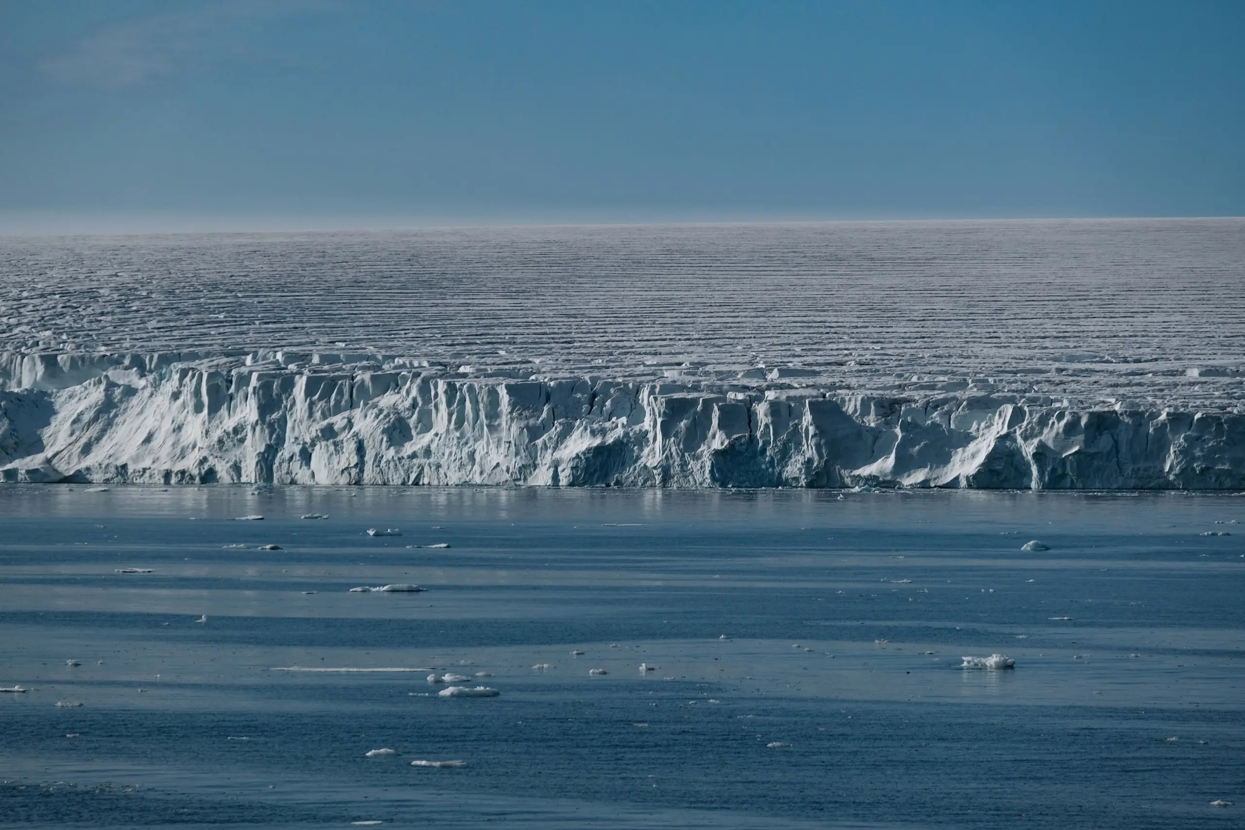 A glacier front meeting the sea with brash ice on the dark water