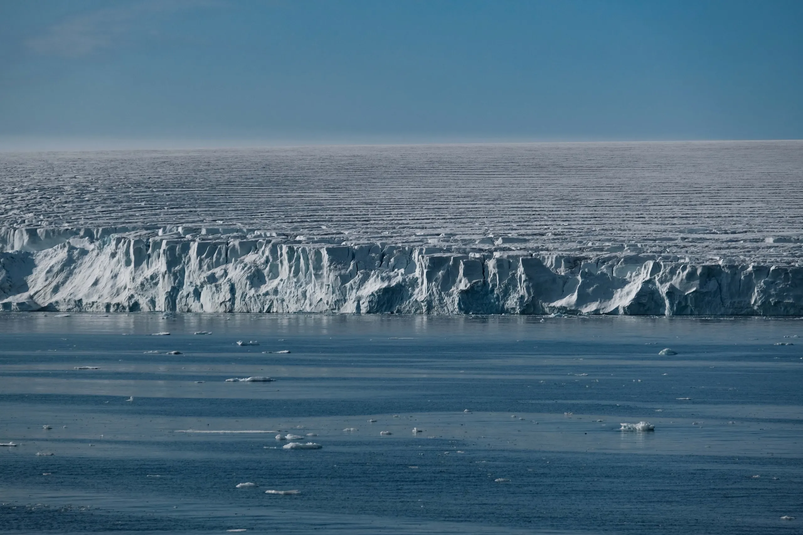 A glacier front meeting the sea with brash ice on the dark water