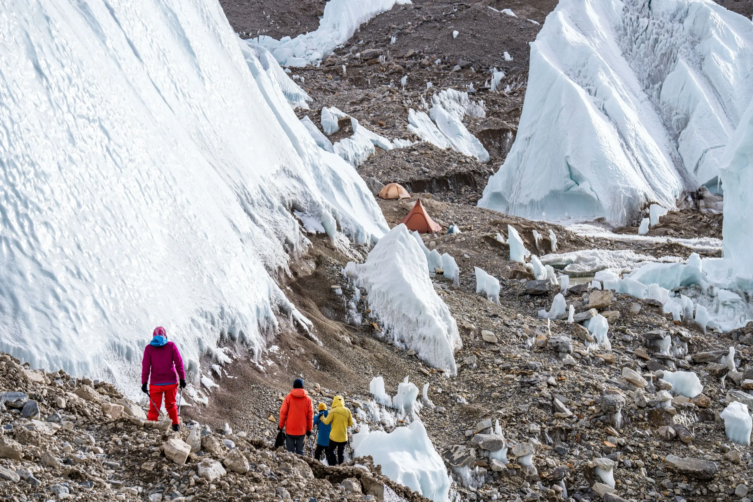 Hikers walking through towering glacier ice on a guided trek
