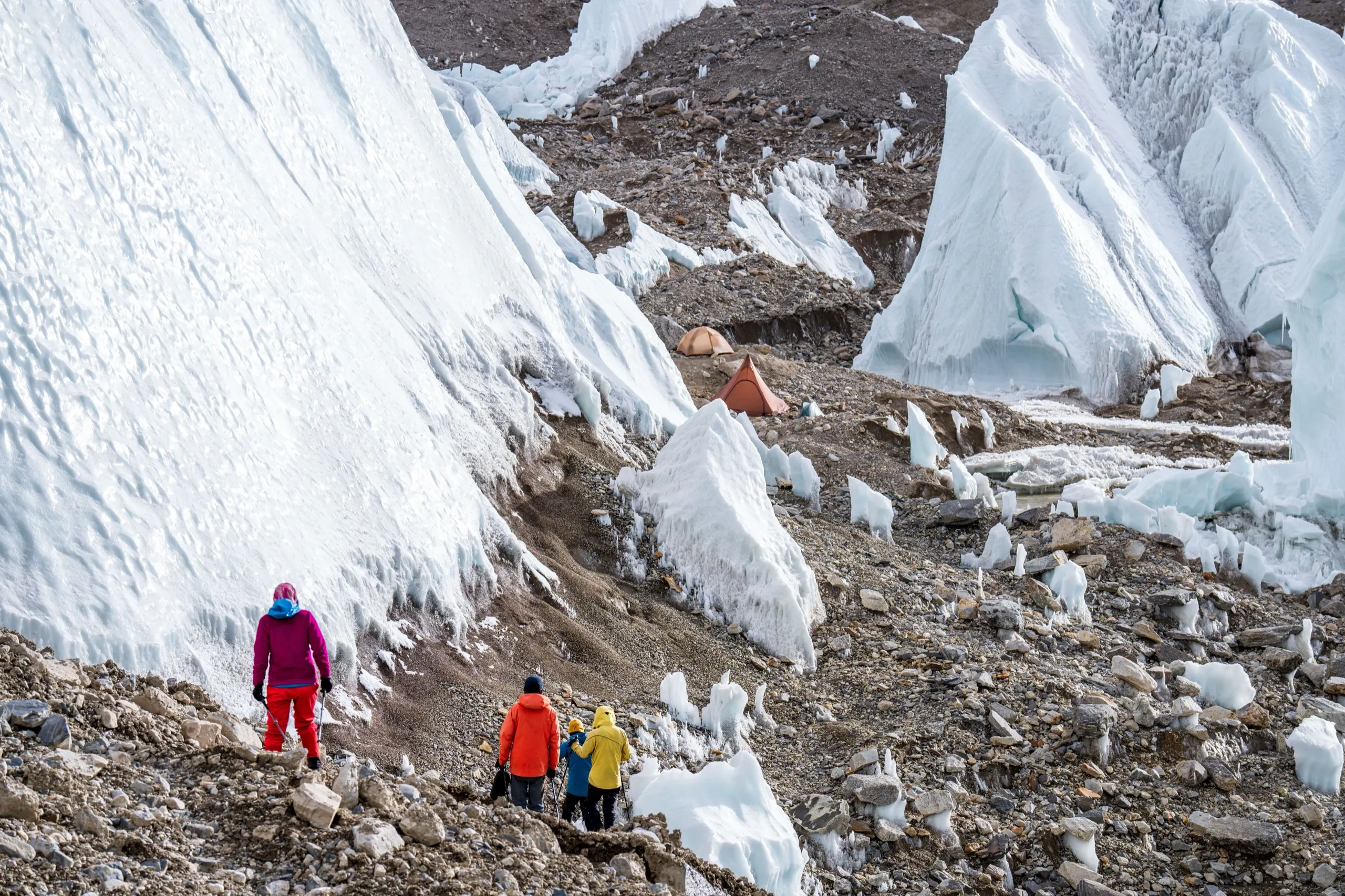 Hikers walking through towering glacier ice on a guided trek