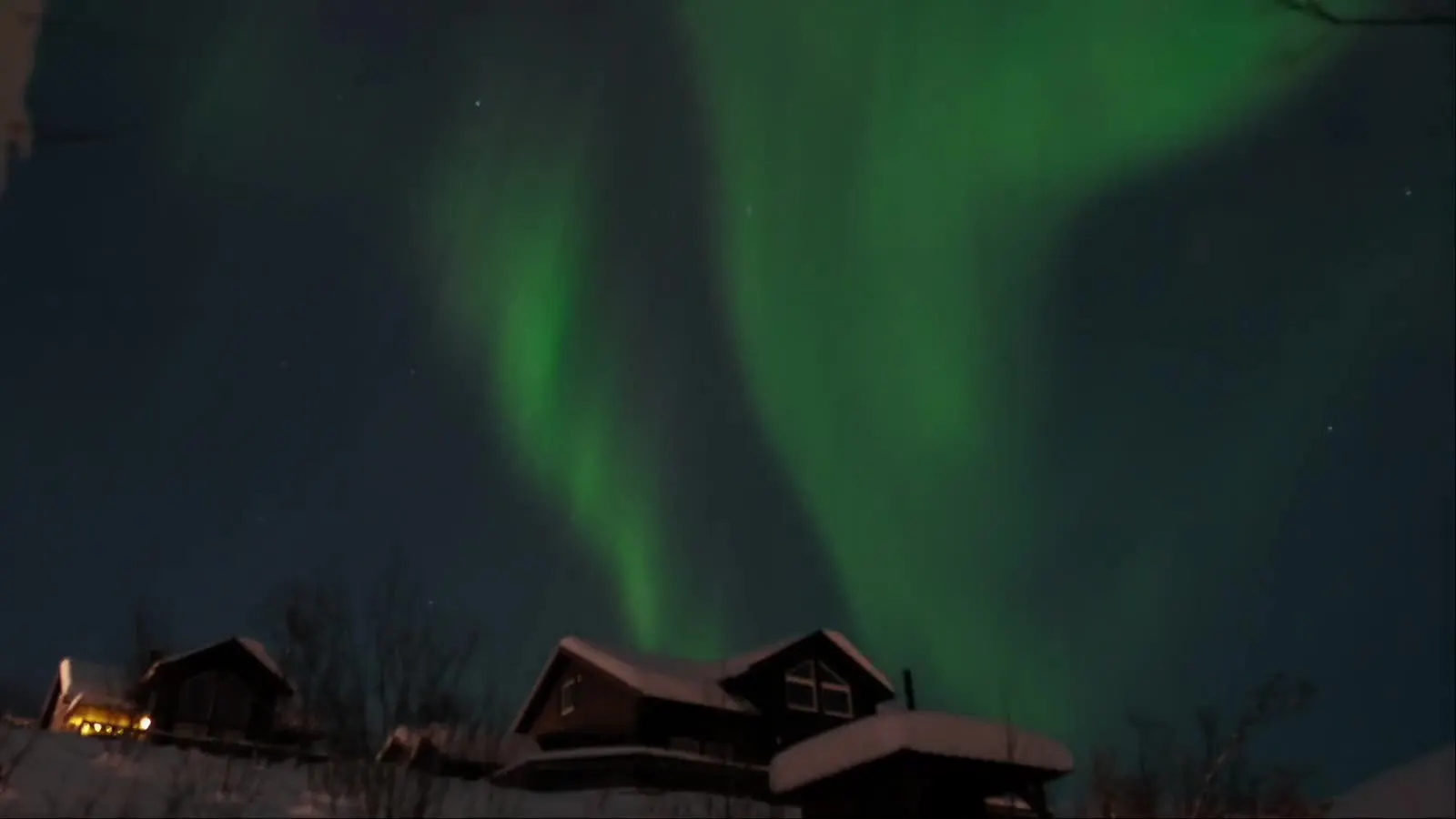 Northern lights over snow-covered Arctic houses on a clear winter night
