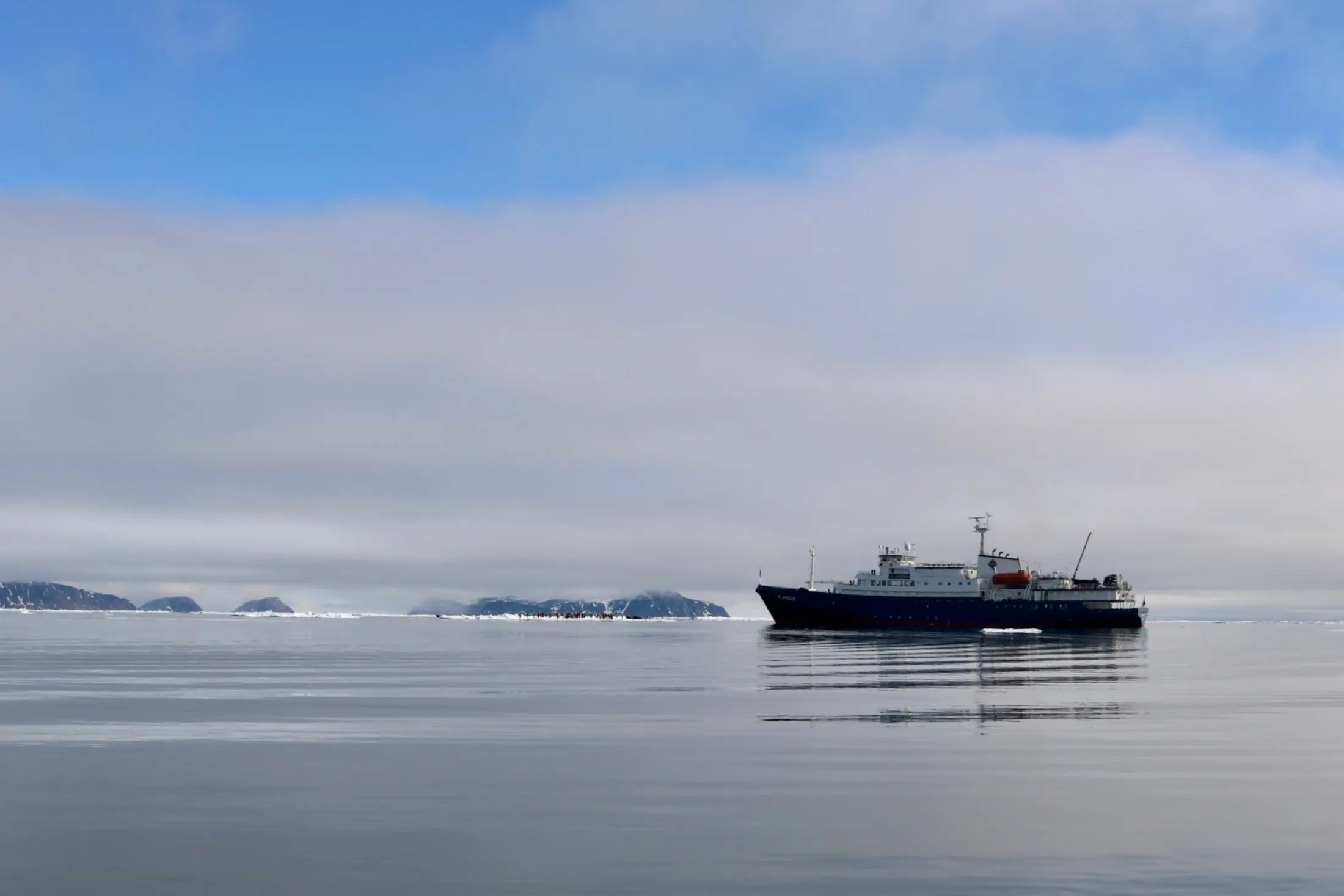A modern expedition cruise ship on calm Arctic water off Svalbard